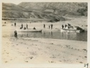 Image of Men working on and near small boats. Two boats heavily loaded with supplies